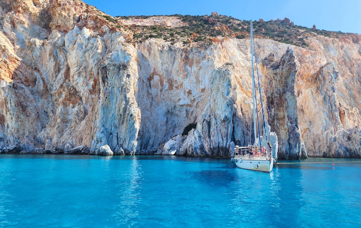Private sailing yacht anchored beside the chalk-white limestone cliffs of a Greek island